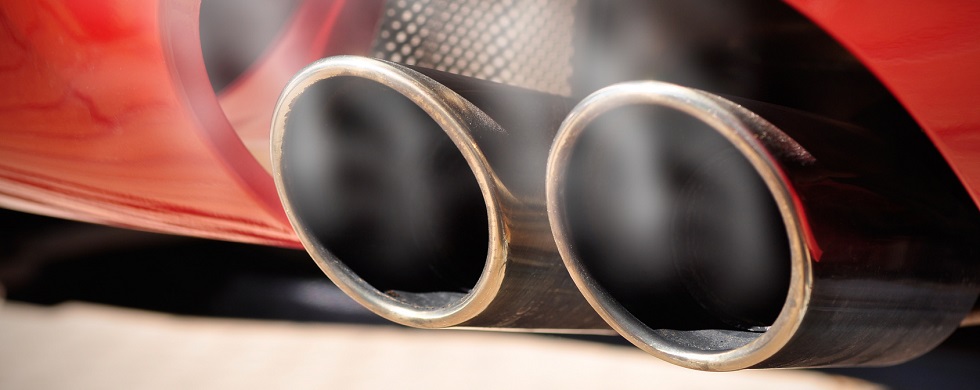 Closeup of exhaust tailpipe with faint white smoke on a red car